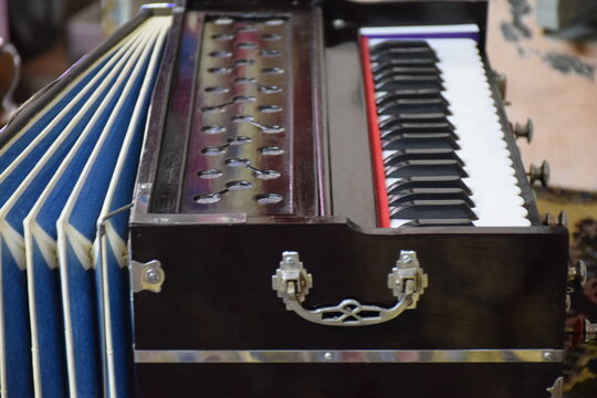 Traditional Indian harmonium musical instrument photo with wooden body, blue bellows, keyboard and metal handles for editorial, cultural poster and music education advertising