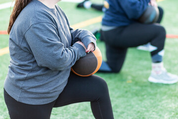 Female athlete on one knee holding a medicine ball