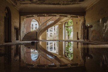 Old flooded abandoned mansion with spiral stair, water reflection