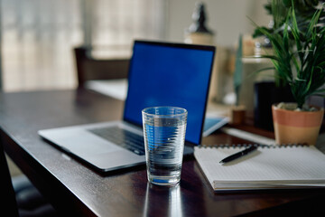 Vaso con agua junto a una computadora