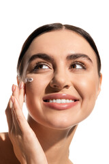 close up view of pleased young woman with face cream on cheek looking away isolated on white.