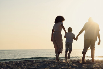 Silhouette, beach and a family with kids by the ocean, holding hands in nature at sunset from the back. Summer, travel or mockup with a mother, father and child having fun while bonding at the sea