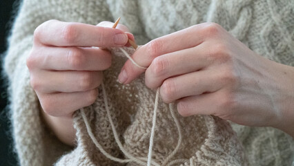 Hands knitting cose-up. Female hands knitting in cose-up. Girl relaxing knitting a warm sweater.