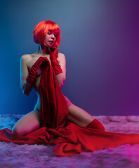sexy naked girl with red hair and red gloves poses erotically with a red cloth in neon light...