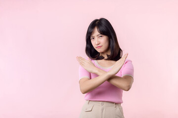 portrait serious young asian woman with cross arm gesture showing stop, no, wrong, denial,...