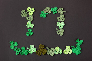 St Patrick's Day concept. Composition made of knitted green shamrocks in the form of the number 17 on a black background. Holiday sign and knitted clover leaf. Copy space, flat lay, place for text