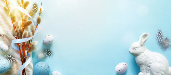 Easter composition with Easter eggs, bunny and natural spring flowers on blue table background