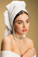 Fototapeta premium young woman in luxurious jewelry posing with towel on head on beige.