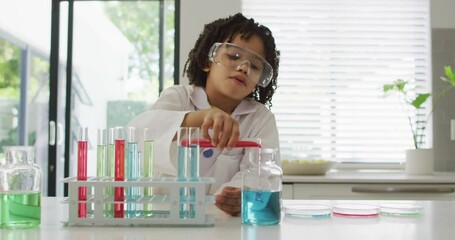Happy biracial boy making chemistry experiments, holding test tube - Powered by Adobe
