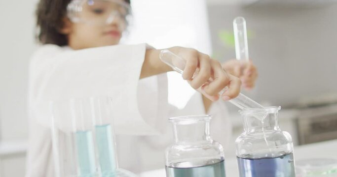 Happy biracial boy making chemistry experiments, holding test tube