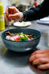 Close up of chef's hands cooking asian pho bo soup on restaurant kitchen
