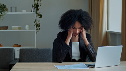 Overloaded tired office worker student african ethnicity woman businesswoman work online check paper documents in laptop feel fatigue throbbing headache touch temples chronic migraine problem stress