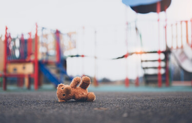 Lost teddy bear toy lying don on playground floor in gloomy day,Lonely and sad brown bear doll lied...