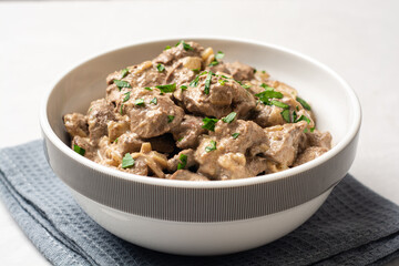 Fried chicken liver with creamy sauce in bowl on concrete background