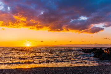 empty beach with surf during beautiful sunrise or sunset with surf, clouds and golden sun