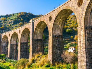 nice old vintage bridge with big arcs and columns among nature with green garneds and blue sky , european old concept landscape