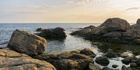 Fototapeta na wymiar sea coast with stones and boulders in the morning. summer vacation background