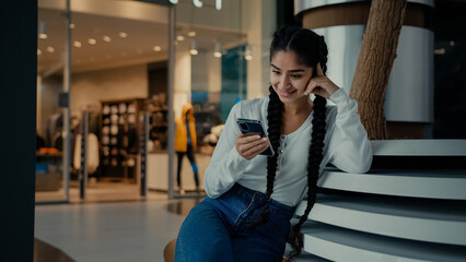 Female student middle-eastern girl businesswoman arabian ethnic woman student shopper chatting on phone sit at shopping center use mobile apps purchasing online read digital news watch internet video