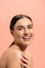 cheerful woman with bare shoulders looking away isolated on pink.