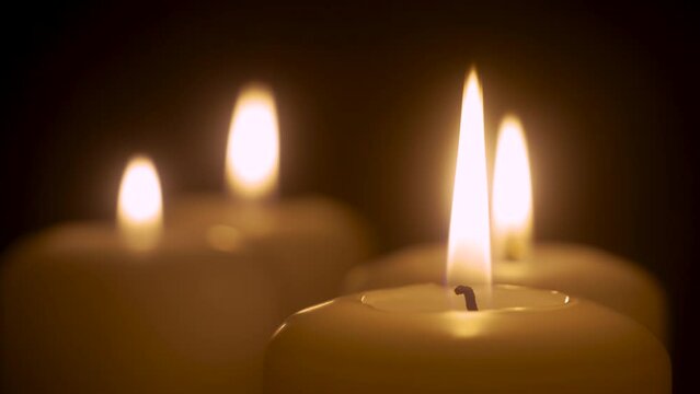 Few white candles burning. Candle lights close up. White paraffin candles with yellow shades burns in room. Lifestyle remembrance celebration religious