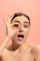 amazed woman with opened mouth showing ok sign isolated on pink.