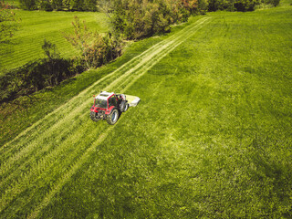 Aerial view of tractor mowing a grass field in the country side