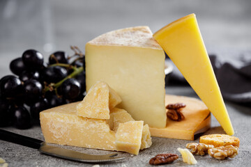 Piece of parmesan cheese close up and different types of cheeses in the background.