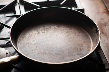 Empty pan on the stove. An old frying pan is heated in a home kitchen.