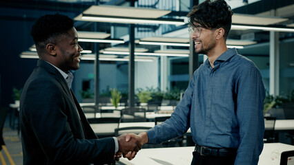 Business meeting two colleagues men shake hands at office accept project teamwork male partnership indian businessman consult african man client agree congratulate successful pact handshaking gesture