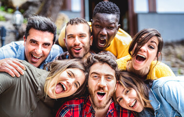 Multicultural men and women taking selfie outdoors on funny party mood - Mixed age range life style concept with young multiethnic hipster people having fun day cheering together - Bright vivid filter