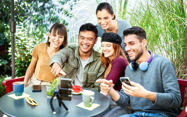 Young people sharing content on streaming platform at coworking cafeteria - Youth life style tech concept with happy milenial influencers having fun vlogging live feeds at coffee bar - Bright filter