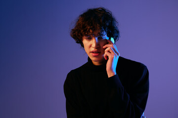 Man with phone in hand teenager online video call and selfies, hipster lifestyle blogger, portrait purple background, mixed neon light, fashion style and trends, copy space