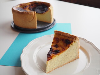 Slice of french custard tart, or flan pâtissier, with the whole tart, on white and blue background