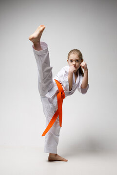 Strong kick in a karate workout, a child girl in a kimono.