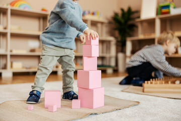 Cropped picture of a kindergartener making blocks tower at nursery. - obrazy, fototapety, plakaty