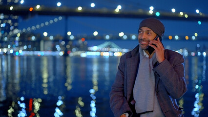 Afro-American man standing at Brooklyn Bridge New York at night - travel photography