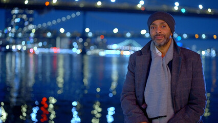 Afro-American man standing at Brooklyn Bridge New York at night - travel photography