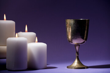 golden christian chalice with candles and purple background
