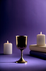 golden christian chalice with candles and purple background