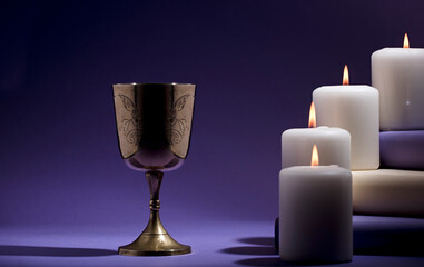 golden christian chalice with candles and purple background