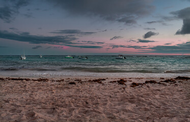 Fishing boats floating in turquoise waters of the Caribbean sea on the island of Barbados at sunset.