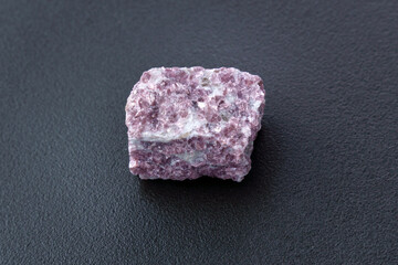 Lepidolite stone on a black background, being a secondary source of lithium, used in batteries