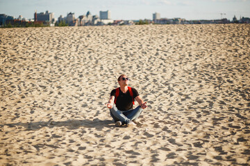 A young tourist man relaxes on a huge city sandy beach in the evening sunlight