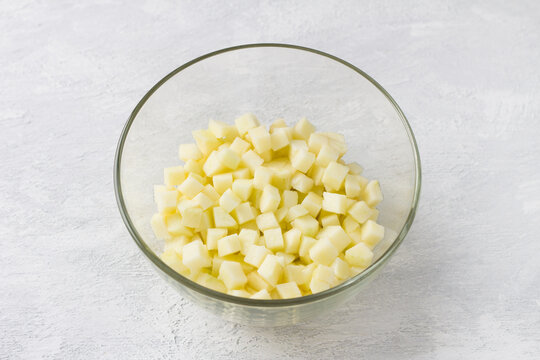 Glass bowl with diced apples on a light gray background. Cooking delicious homemade food