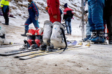 Low shot of sking boots on skis in snow showing crowd of people in winter wear playing in snow, sking, sliding, at snow point in lahul, manali solang a popular tourist spot during winters