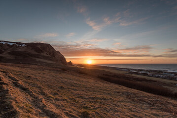 Fototapeta na wymiar Sunset above the ocean with view on the coastine in Vík í Mýrdal, south coast of Iceland.
