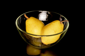 Two ripe yellow pears in glassware, close-up, isolated on black.