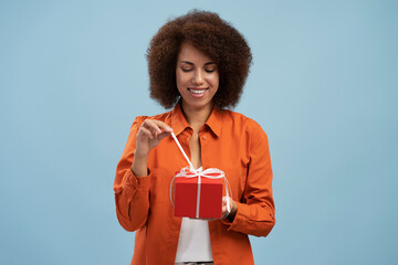 Portrait of african american woman opening gift box, unwrapping birthday present