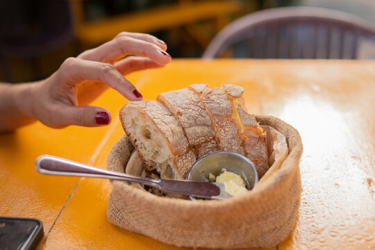 Caucasian woman hands eating bread garnishing with butter knife at restaurant table