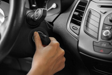 A woman's hand starts the car with a key, close-up.